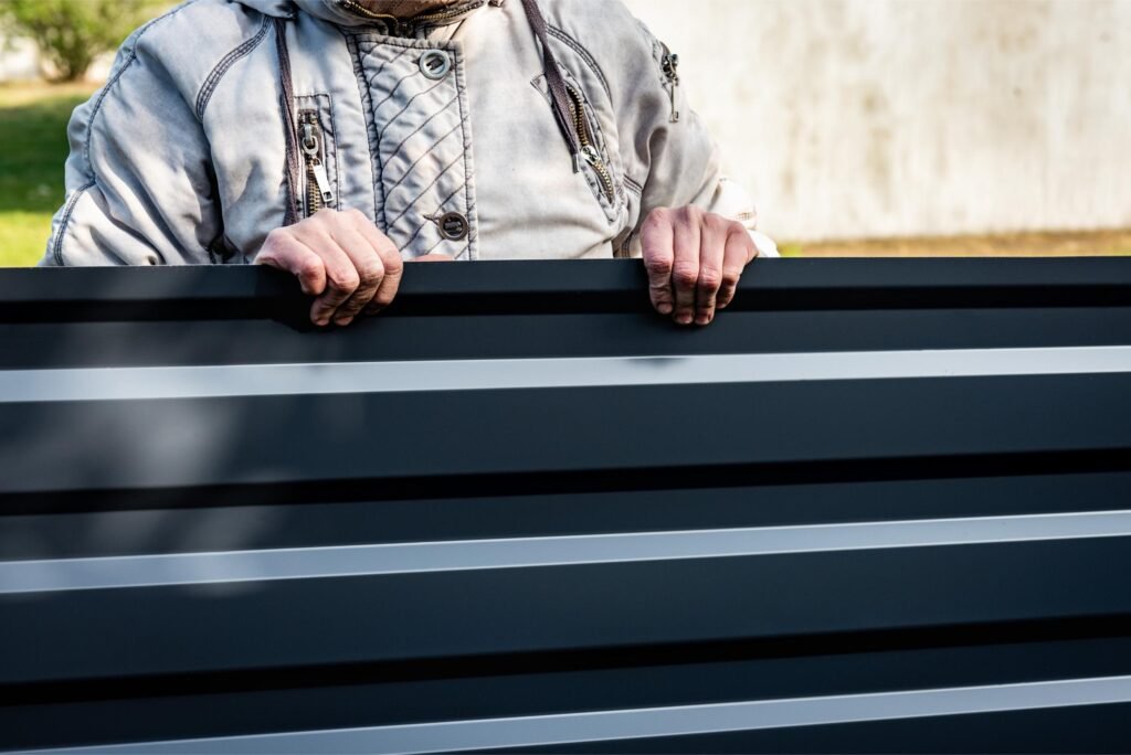 personne tenant une plaque de métal profilée de couleur gris foncé